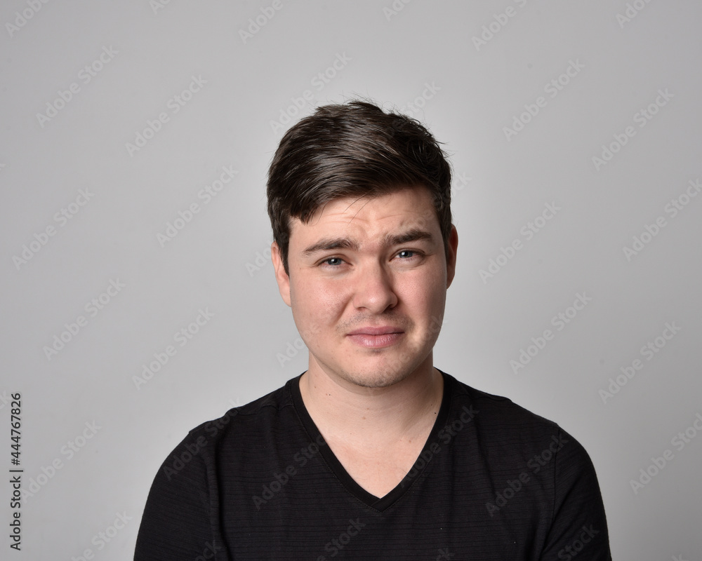 Close up head and shoulders portrait of a brunette. young man with a variety of expressive facial expressions. Isolated on a light grey studio background. Close up head and shoulders portrait of a brunette. young man with a variety of expressive facial expressions. Isolated on a light grey studio background.