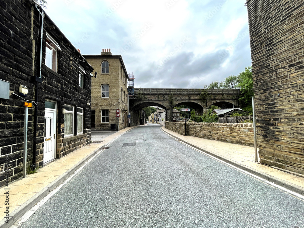 View down, New Road, with Victorian buildings, and an old stone viaduct in, Mytholmroyd, Hebden Bridge, UK