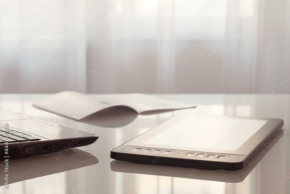 A graphic tablet and a laptop are lying on a glass table. A graphic tablet and a laptop are lying on a glass table.