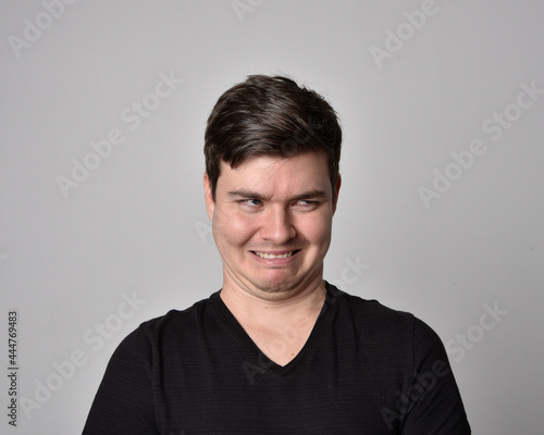 Close up head and shoulders portrait of a brunette. young man with a variety of expressive facial expressions. Isolated on a light grey studio background. © faestock