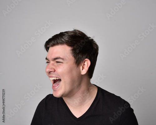 Close up head and shoulders portrait of a brunette. young man with a variety of expressive facial expressions. Isolated on a light grey studio background. © faestock