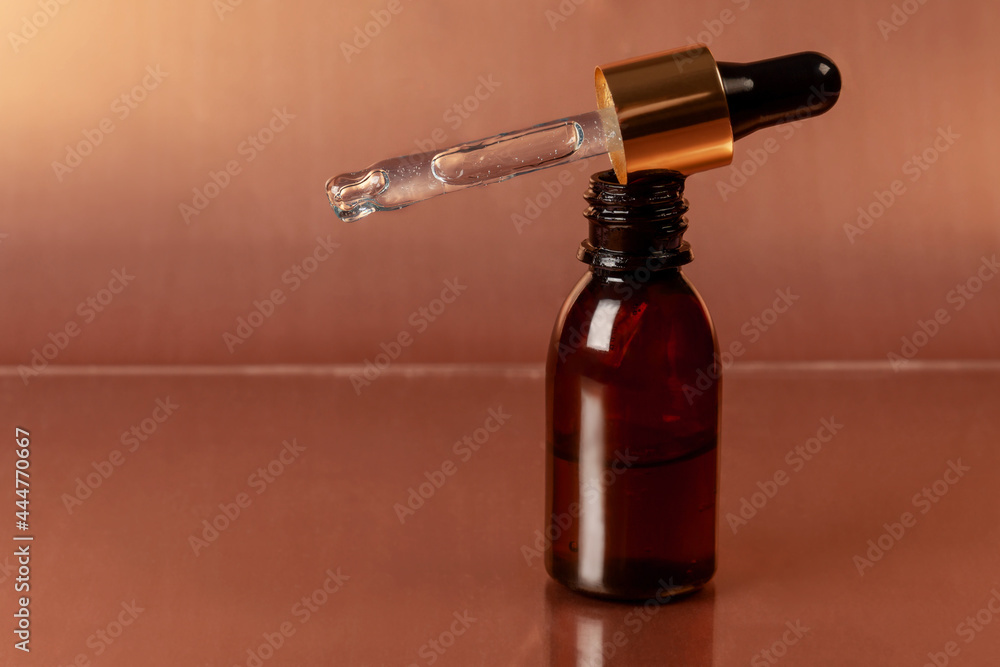 Cosmetic pipette close-up and bottle of cosmetic product, oil or hyaluronic acid on a gold background. Cosmetic pipette close-up and bottle of cosmetic product, oil or hyaluronic acid on a gold background.