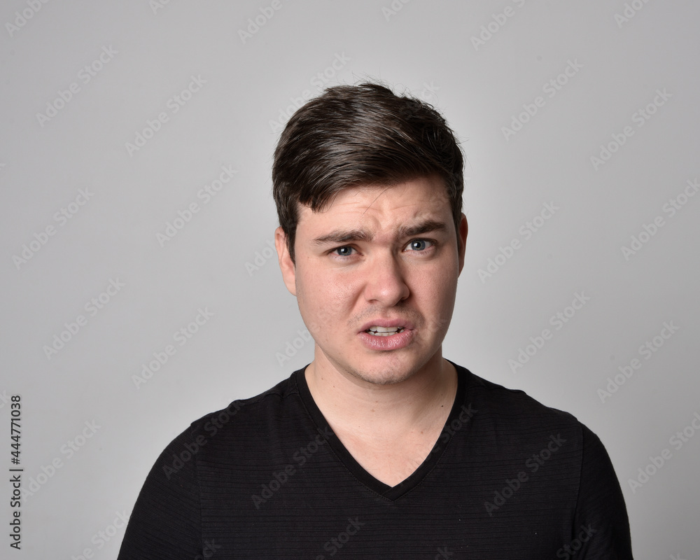 Fototapeta premium Close up head and shoulders portrait of a brunette. young man with a variety of expressive facial expressions. Isolated on a light grey studio background.