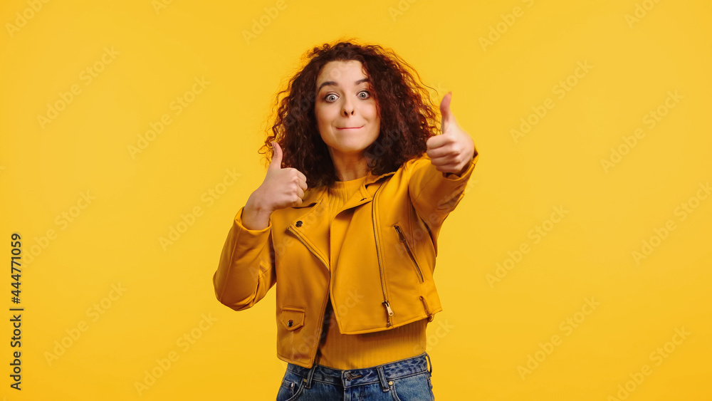 curly young woman showing thumbs up isolated on yellow curly young woman showing thumbs up isolated on yellow