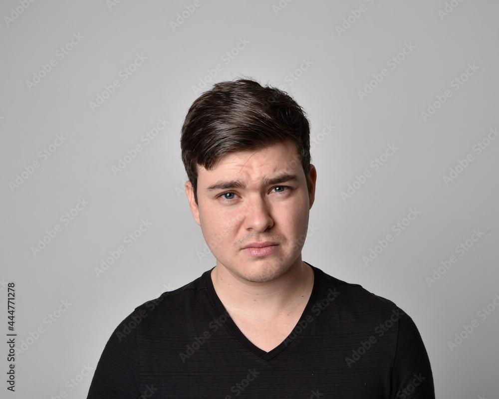Fototapeta premium Close up head and shoulders portrait of a brunette. young man with a variety of expressive facial expressions. Isolated on a light grey studio background.