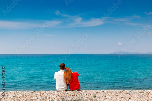 a couple are sitting at the seaside