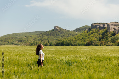 beautiful brunette woman walking through a field of wheat looks at the nature © dmitriisimakov