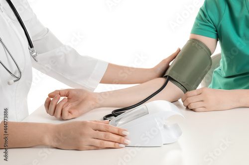 Doctor checking blood pressure of woman at table on white background  closeup