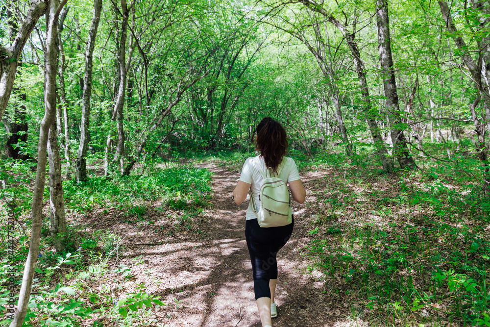 woman walking through the green forest nature journey