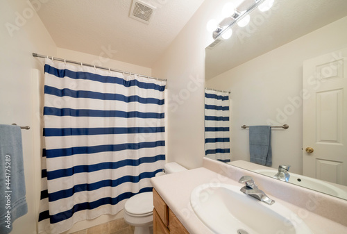 Interior of a bathroom with vanity sink and closed blue and white striped shower curtain photo