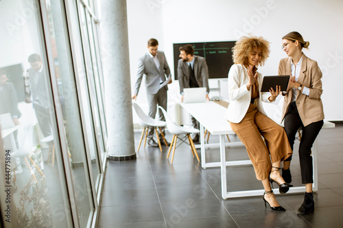 Young women using digital tablet in modern office in front of their team