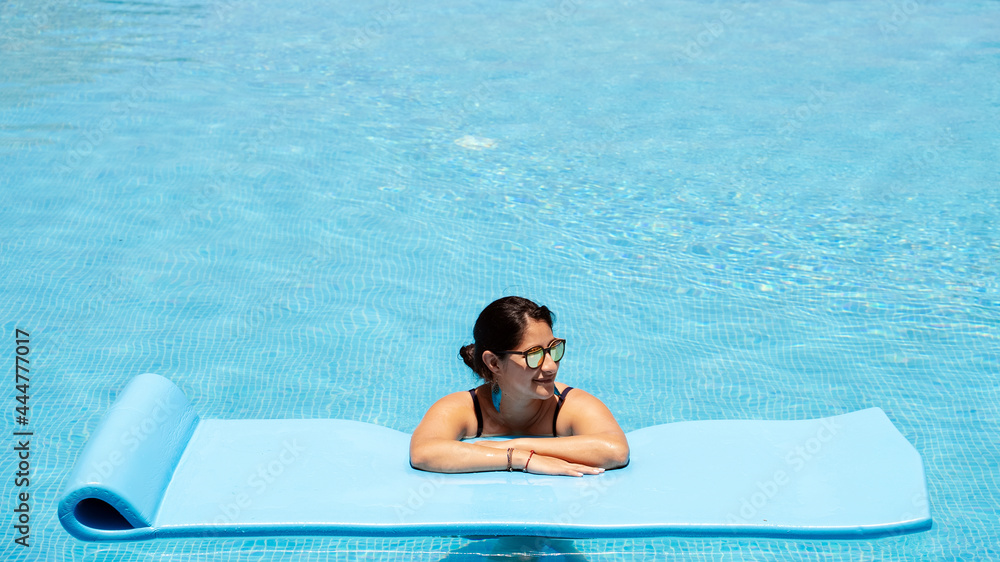 Happy Hispanic woman relaxing and tanning in swimming pool