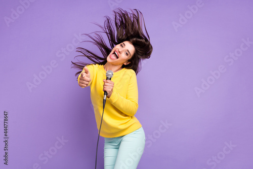 Photo of cheerful young positive woman point finger you fly hair mic singer karaoke isolated on purple color background