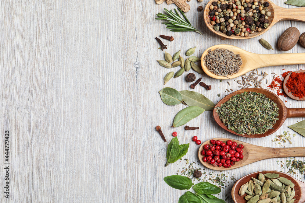 Different natural spices and herbs on light wooden table, flat lay. Space for text Different natural spices and herbs on light wooden table, flat lay. Space for text