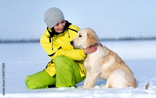 Beautiful girl with lovely young retriever dog outside in winter