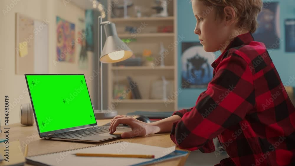 Smart Young Boy Researching Homework on Laptop Computer with Green Chroma Key Screen Display Mock Up. Teenager Browsing Educational Research, Chatting on Social Media, Studying School Material. Smart Young Boy Researching Homework on Laptop Computer with Green Chroma Key Screen Display Mock Up. Teenager Browsing Educational Research, Chatting on Social Media, Studying School Material.