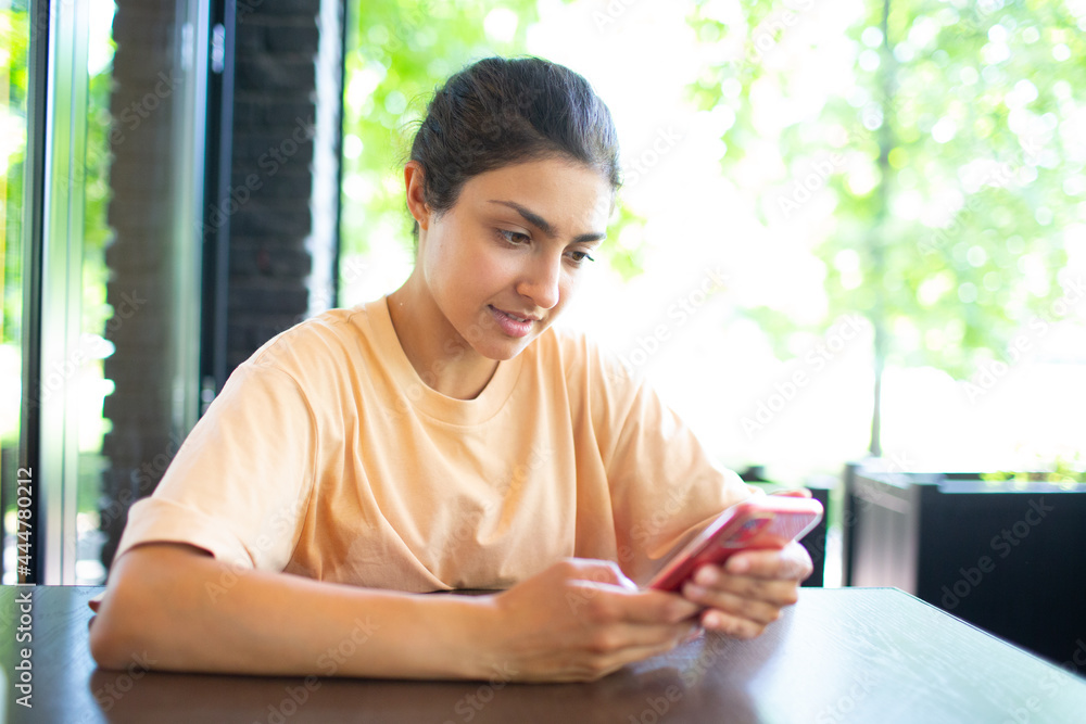 Happy young Indian woman chatting on mobile phone sitting outdoor cafe Happy young Indian woman chatting on mobile phone sitting outdoor cafe
