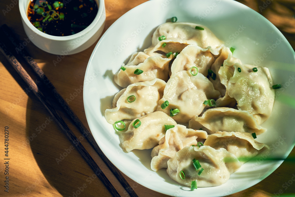 Classic Chinese boiled dumplings with meat and spicy soy sauce in a white plate. Chinese cuisine Classic Chinese boiled dumplings with meat and spicy soy sauce in a white plate. Chinese cuisine