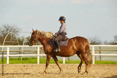 Young girl rides a horse with a light mane