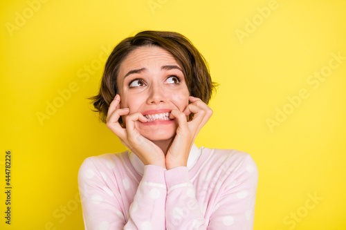 Photo of young girl bite fingers teeth afraid scared panic terrified look empty space isolated over yellow color background