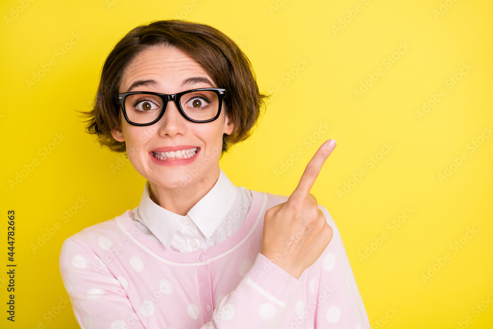 Photo portrait amazed funny girl in glasses pointing finger empty space isolated vibrant yellow color background Photo portrait amazed funny girl in glasses pointing finger empty space isolated vibrant yellow color background