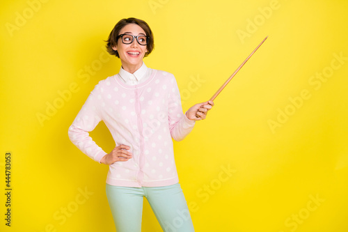 Photo portrait of curious funny girl in glasses pointing at school teaching looking empty space isolated vivid yellow color background photo
