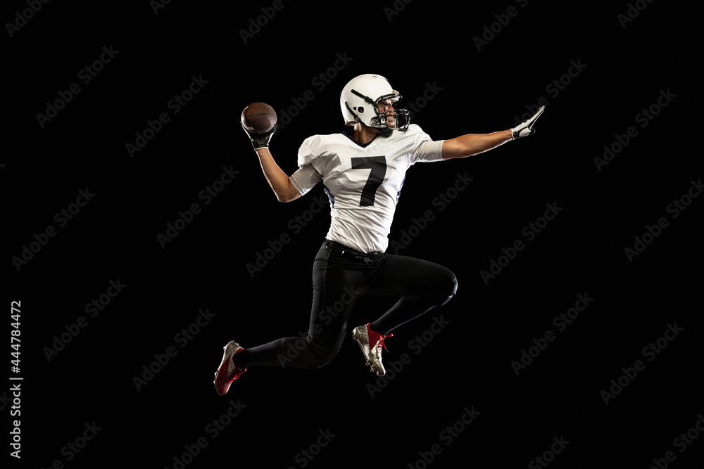 Portrait young American football player, athlete in black white sports uniform training isolated on dark studio background. Concept of professional sport, championship, competition.