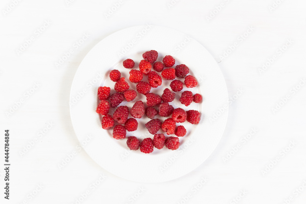 Ripe red raspberries on white plate Ripe red raspberries on white plate
