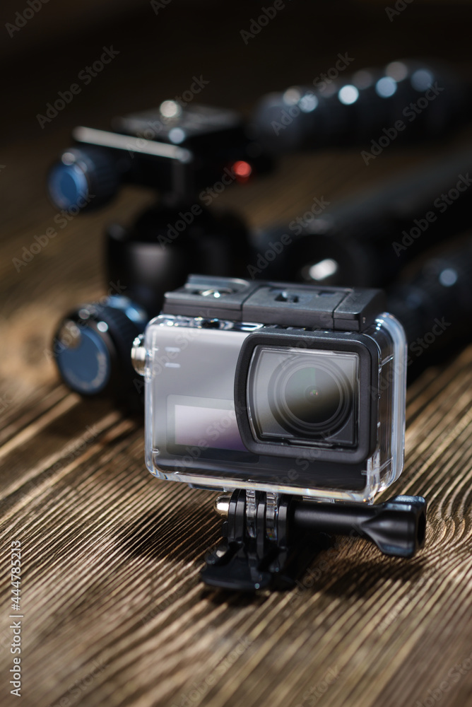 Black action camera on brown wooden tabletop.