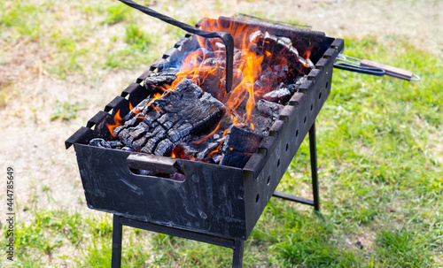 Brazier or grill with burning charcoal close-up. The man is stirring the coals with a hot poker. Picnic, cooking on an open fire in the front or backyard. Charcoal grilling.