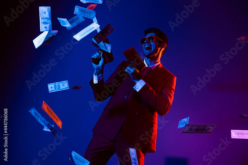 Photo of funky charming young man wear glamour costume eyewear dancing shooting money gun isolated dark blue color background