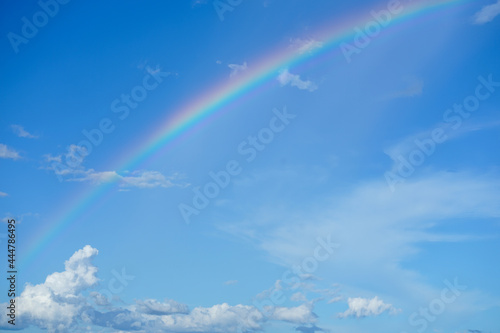 clear blue sky with cloudscape and rainbow crossing the sky