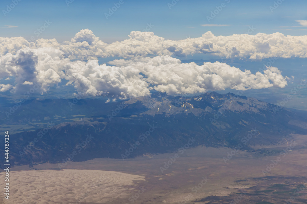 Overview on the airplane of fluffy clouds in scenic landscape of mountain Arizona with the mountain range