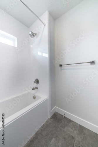 Bathtub inside a bathroom with dark gray tiles flooring and white wall