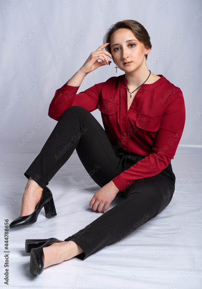girl posing in front of the camera. novice model on a gray background in black pants and shoes and in a red blouse. teen looks at us girl posing in front of the camera. novice model on a gray background in black pants and shoes and in a red blouse. teen looks at us