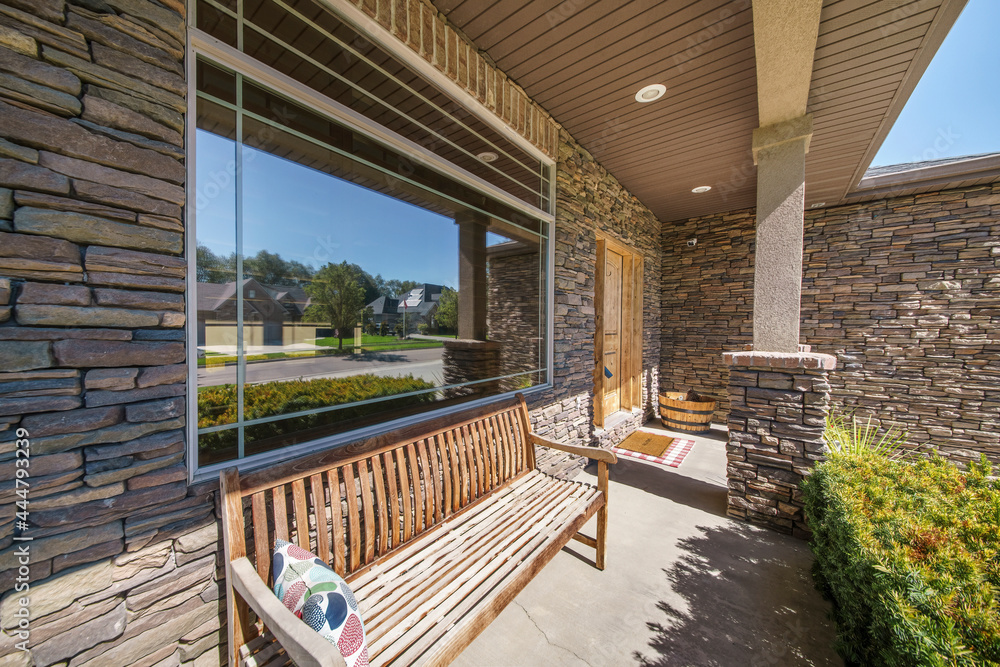 Front porch exterior of a house with stone bricks and wooden bench
