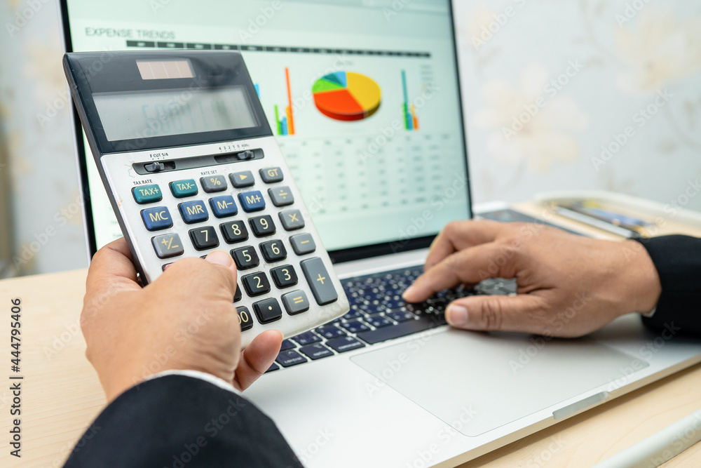 Asian accountant working and analyzing financial reports project accounting with chart graph and calculator in modern office, finance and business concept. Asian accountant working and analyzing financial reports project accounting with chart graph and calculator in modern office, finance and business concept.