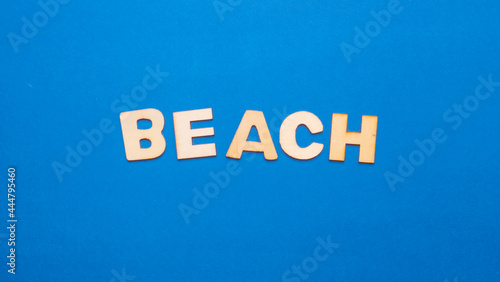 
Wooden letters with the word "beach" horizontally in the center of the image on a blue background