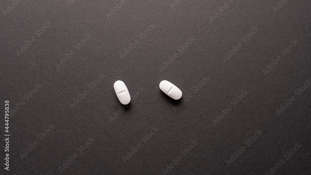 two white pills on black background two white pills on black background
