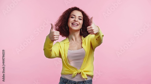 young happy woman showing thumbs up isolated on pink