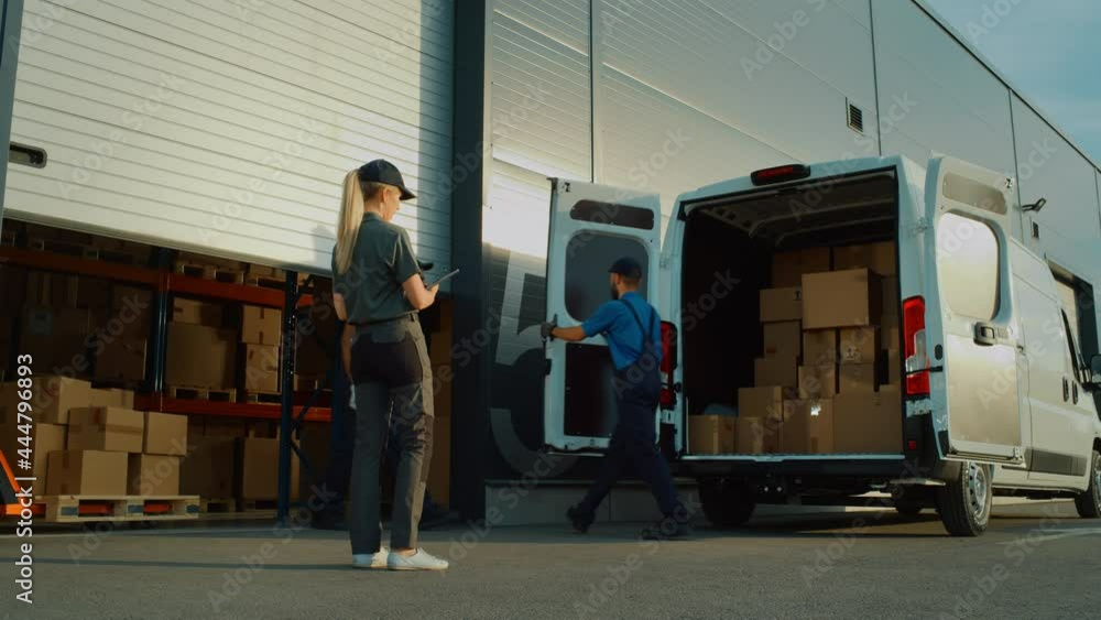 Outside of Logistics Distributions Warehouse Delivery Truck: Manager Using Tablet Computer, Workers Start Unloading Cardboard Boxes, Online Orders, Purchases, E-Commerce Goods. Pan Wide Shot Outside of Logistics Distributions Warehouse Delivery Truck: Manager Using Tablet Computer, Workers Start Unloading Cardboard Boxes, Online Orders, Purchases, E-Commerce Goods. Pan Wide Shot