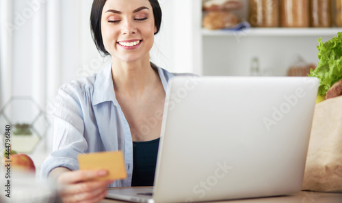 Smiling woman online shopping using computer and credit card in kitchen © lenets_tan