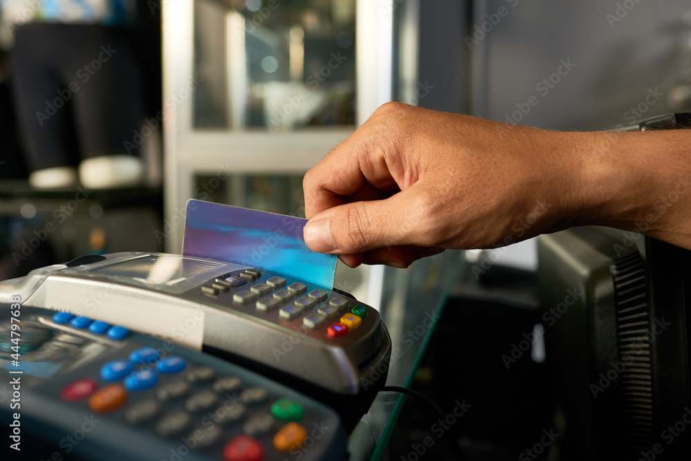 Hand of cashier swiping credit card with POS machine when accepting payment Hand of cashier swiping credit card with POS machine when accepting payment