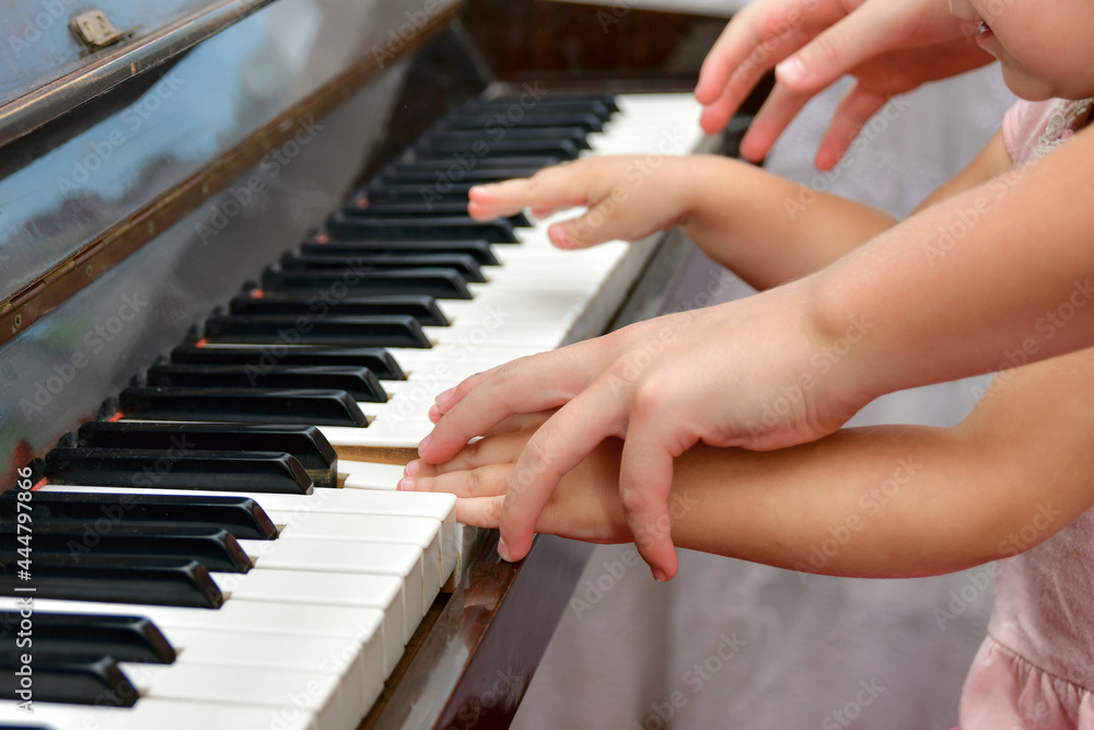 Fototapeta premium The teacher shows the child how to play the piano correctly. The concept of teaching children in a music school.