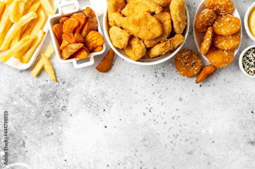 Obraz na plátne Chicken nuggets, strips, french fries, fried potatoes, ketchup and cheese sauce on a light background