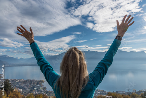 Happy blonde woman admiring the landscape and raising her arms.