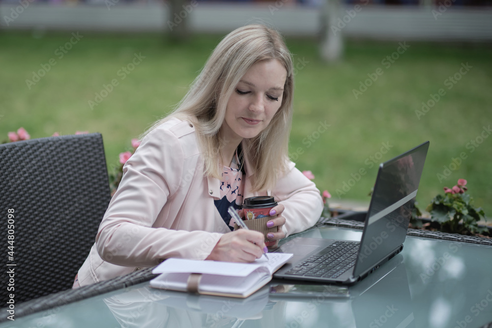 Beautiful woman working with laptop, on the street of old city on summer day, waist up Beautiful woman working with laptop, on the street of old city on summer day, waist up
