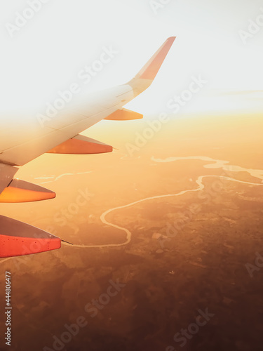 Hazy airplane wing view sunny cinematic panorama during flight over land copy paste vertical background photo