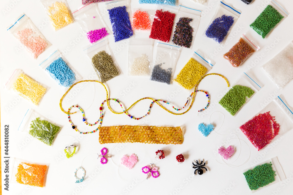 Creative, bright and colorful beads on the white table. Handicraft workplace. Beautiful diy jewelry and calming stress relieving hobby and activity Creative, bright and colorful beads on the white table. Handicraft workplace. Beautiful diy jewelry and calming stress relieving hobby and activity