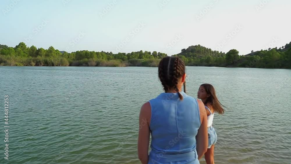 mujer y niña disfrutando en lago.